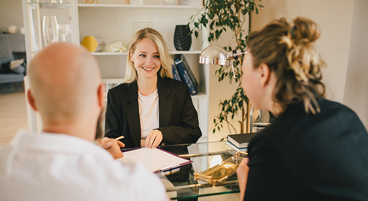 Happy couple having conversation with real estate agent in the office